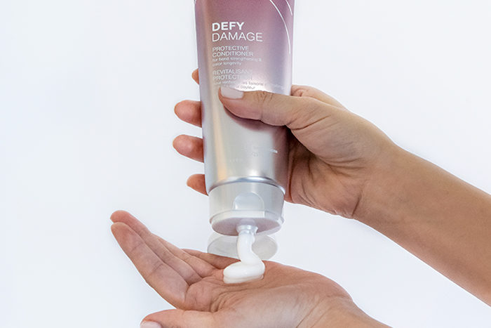 defy-damage-conditioner-in-hand Defy damage conditioner showing product in hand